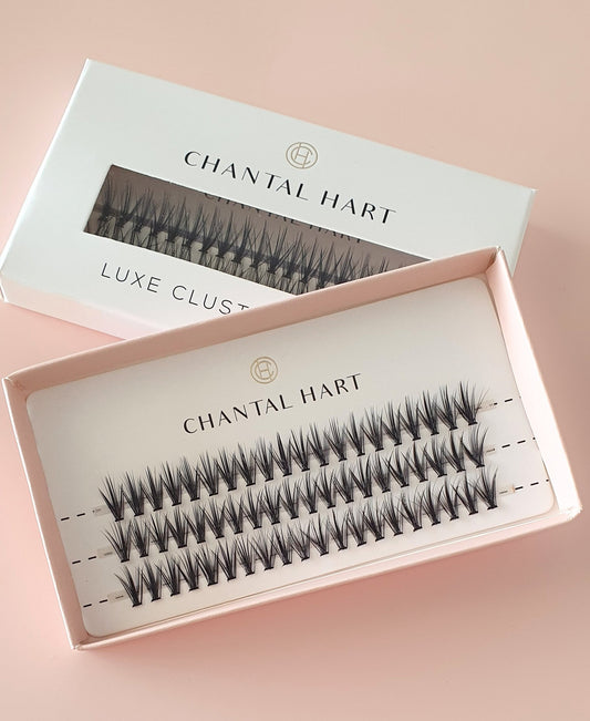 A set of Chantal Hart Luxe Lashes displayed in an open pink box, with the lashes visible through a clear lid. The lashes are arranged in rows, showing different lengths and thicknesses.