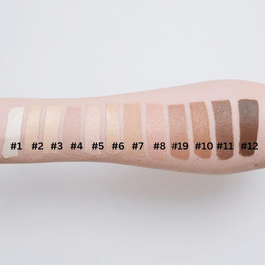 Makeup swatches on a person's arm with labeled shades against a white background