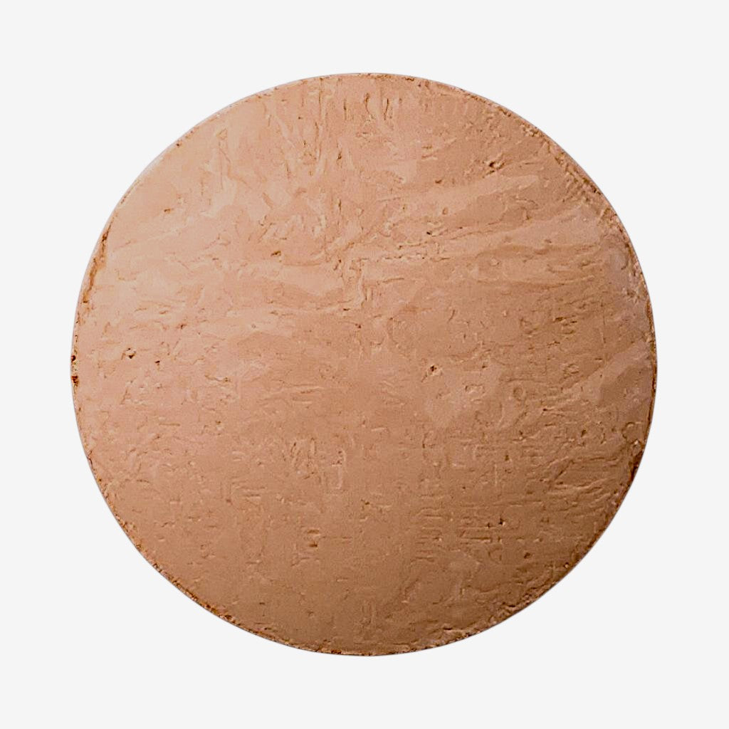 Round light beige foundation dome of makeup on a white background