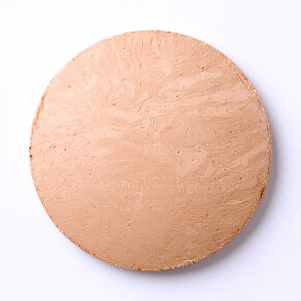 Round light- medium beige foundation dome of makeup on a white background