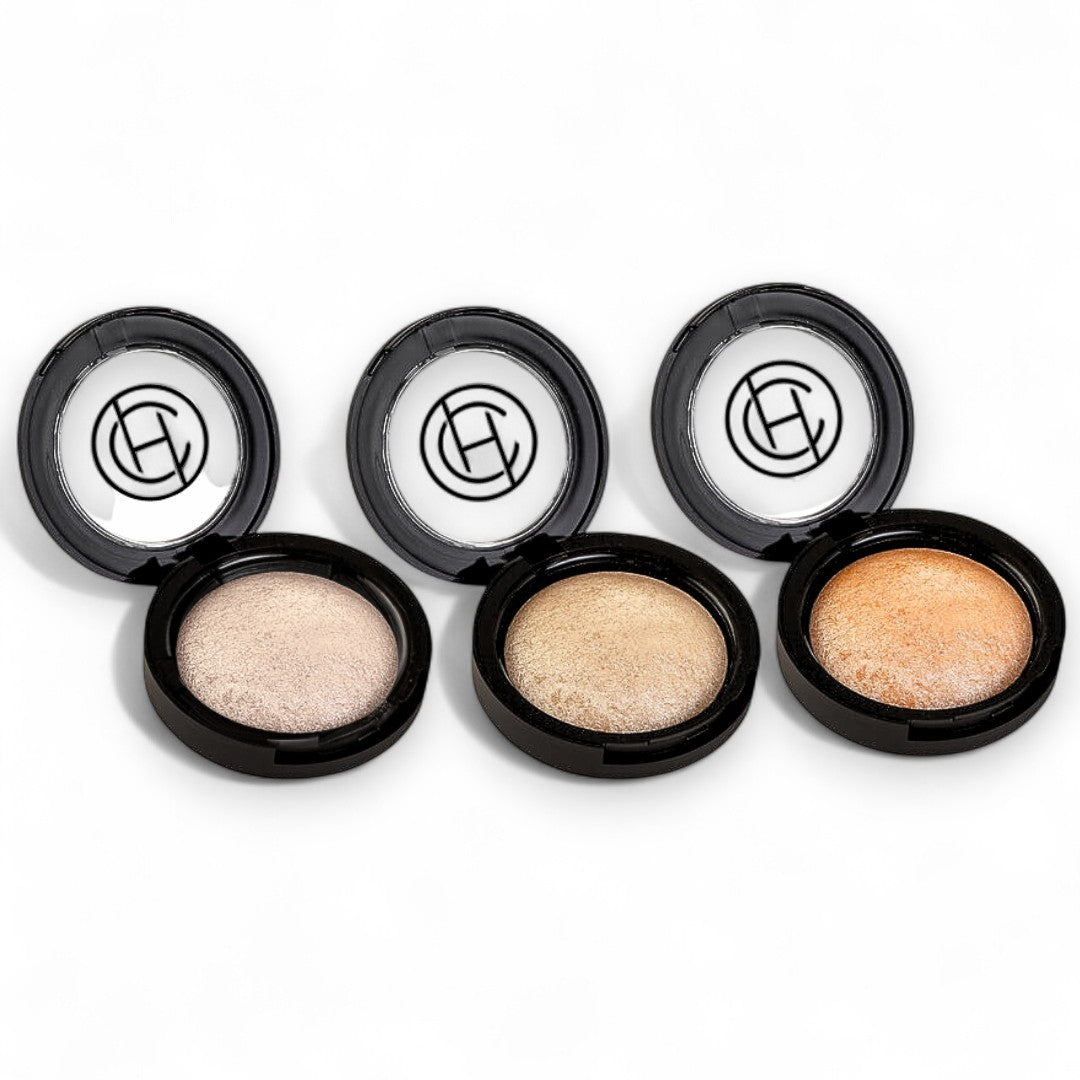 Four open makeup compact cases with different shades of shimmer powder on a white background