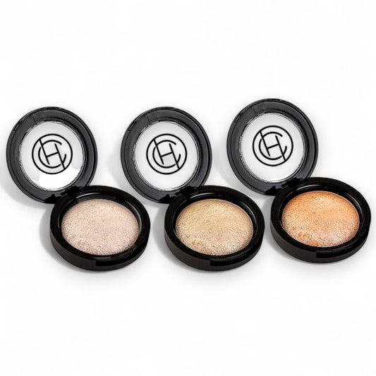 Four open makeup compact cases with different shades of shimmer powder on a white background